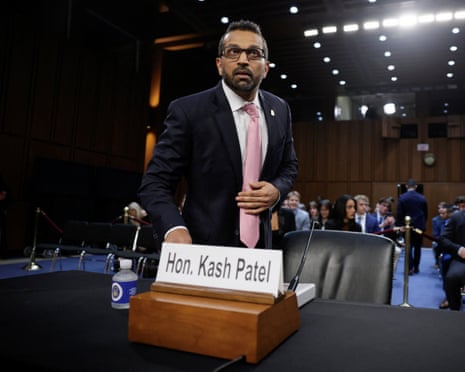 a man stands near a table with a placard bearing his name